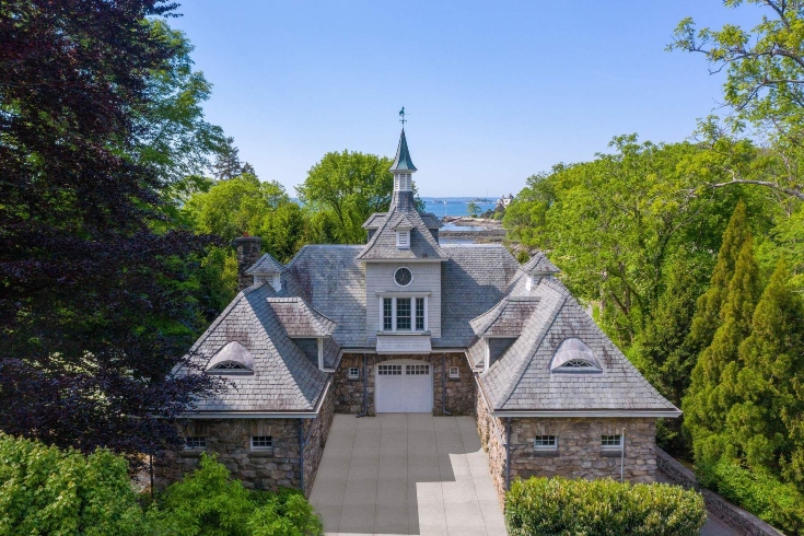 A stone carriage house with a clock tower on a New England estate